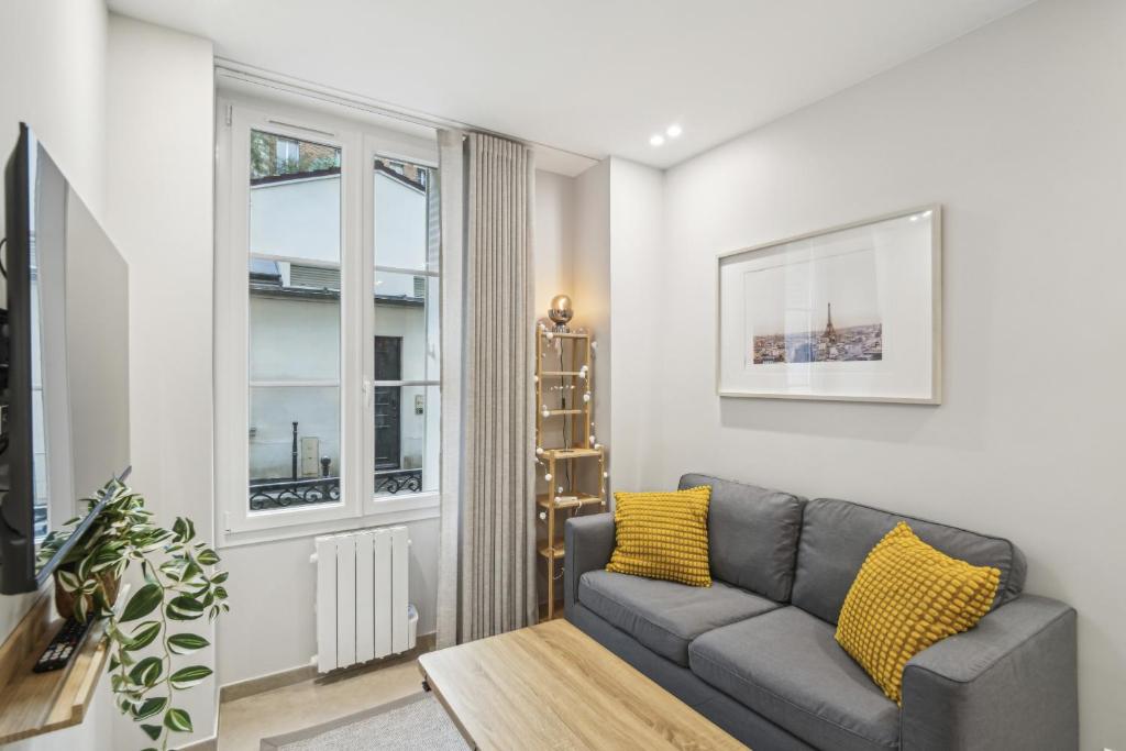 un salon avec un canapé et une fenêtre dans l'établissement Appartement Elegant 1BDR-2P - Paris Expo, à Paris