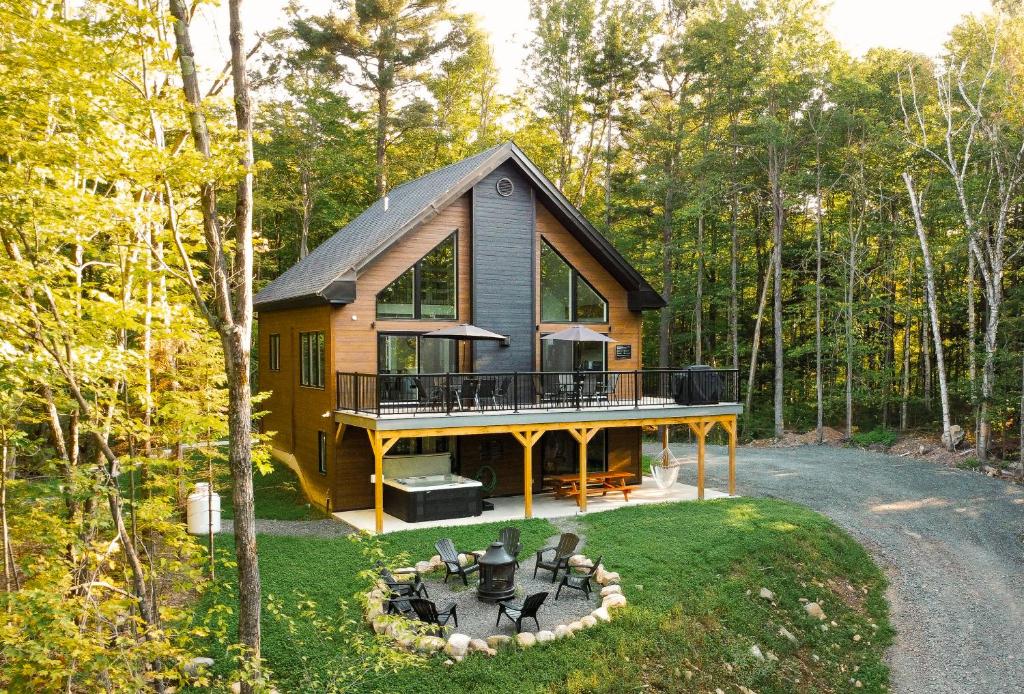 a house in the woods with a deck and chairs at Chalet Le Silverson in Brownsburg