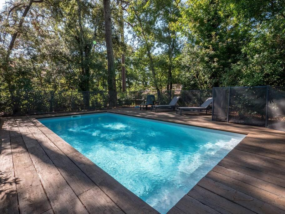 - une piscine dans une cour avec une terrasse en bois dans l'établissement Villa Les Pins à deux pas de la plage PYLA SUR MER, à La Teste-de-Buch