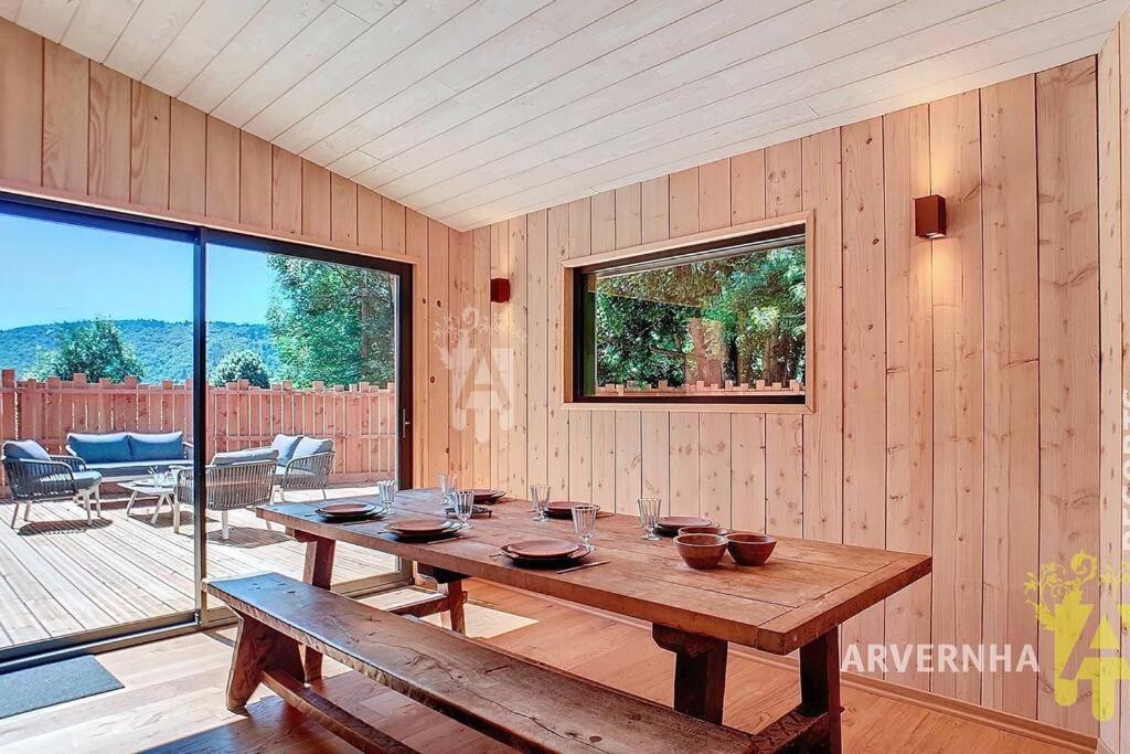 a wooden dining room with a table and a patio at La Montagne in Chambon-sur-Lac
