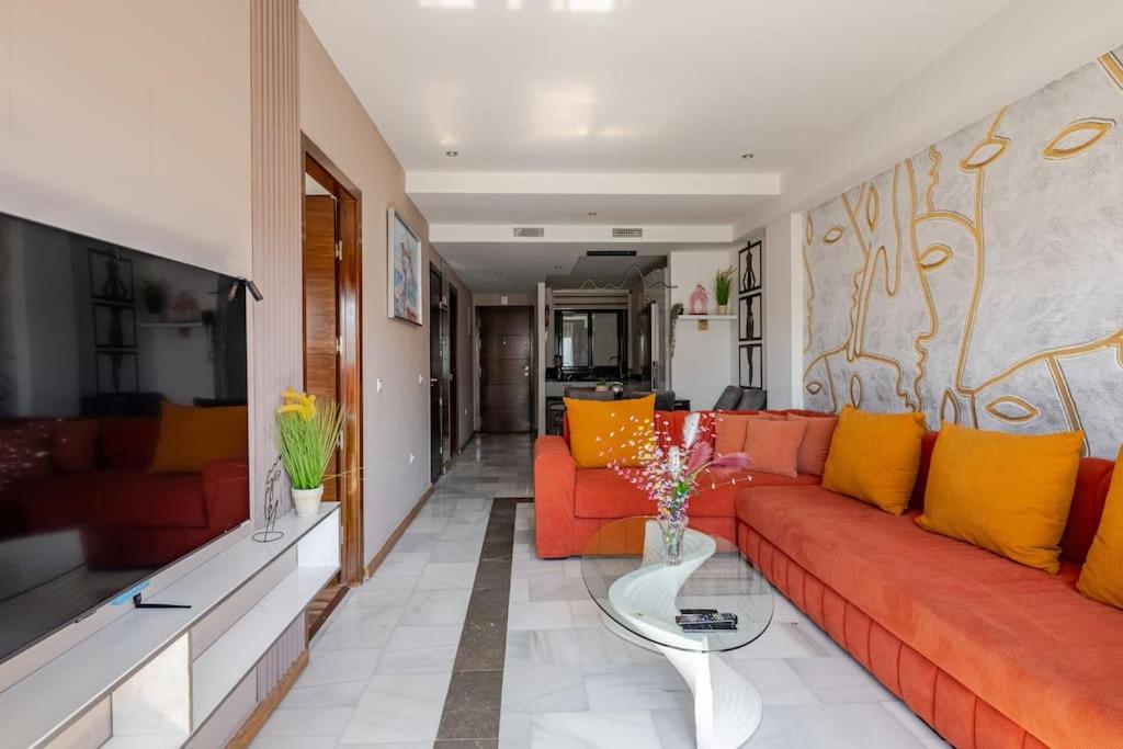 a living room with a red couch and yellow pillows at Sunlit Orange Suite - TGV and Marina Access in Tangier