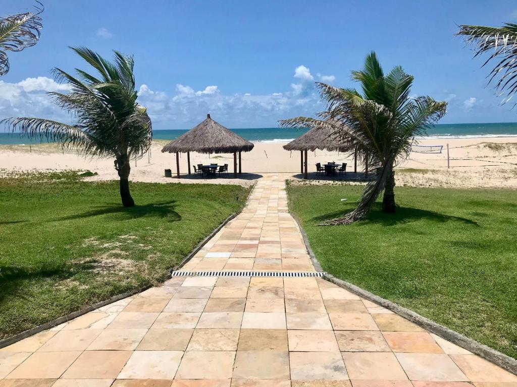 a walkway leading to a beach with palm trees at Terramaris - Paraíso Pé na areia in Aquiraz