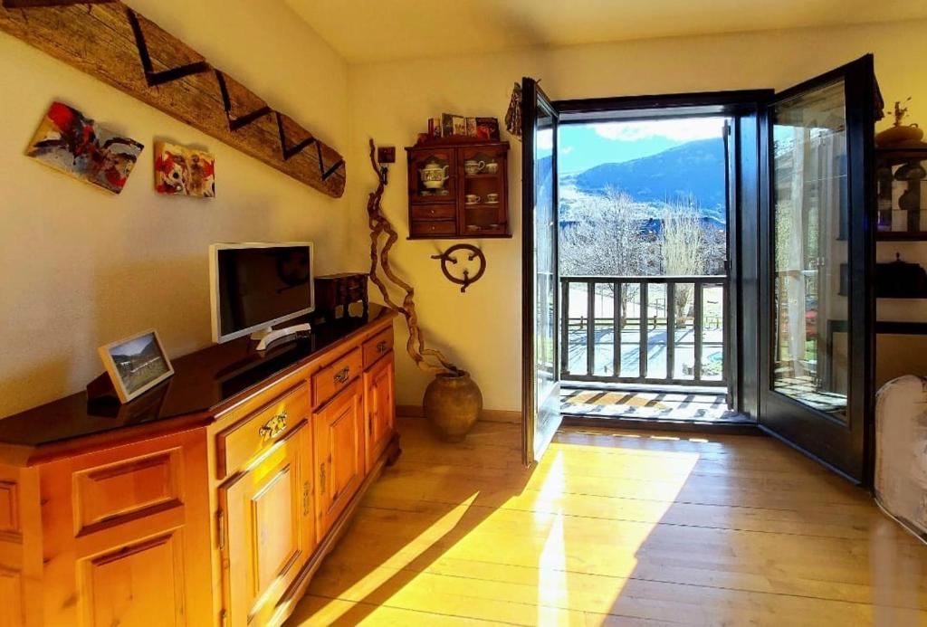 Una habitación con televisión y puerta a un balcón. en Confort excelente- Chimenea, sol y bien equipado - Falcó 10, en Pla de l'Ermita