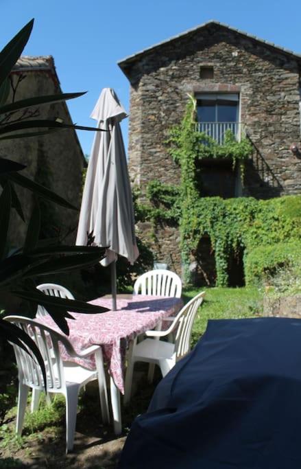 - une table avec un parasol et deux chaises blanches dans l'établissement L'abri cévenol, à Saint-André-de-Valborgne