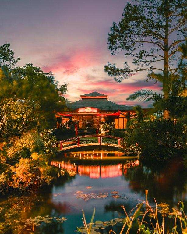 a building with a bridge over a pond at Pousada Mevlana Garden in Barra de Ibiraquera