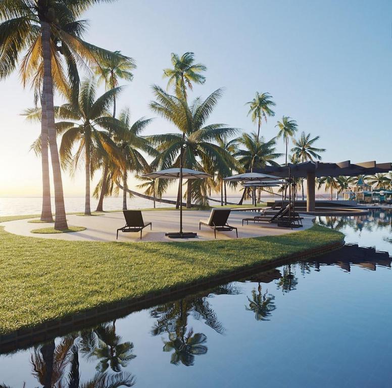 a resort with palm trees and a pool with chairs and umbrellas at Porto Alto Resort GAV em Muro Alto in Cupe