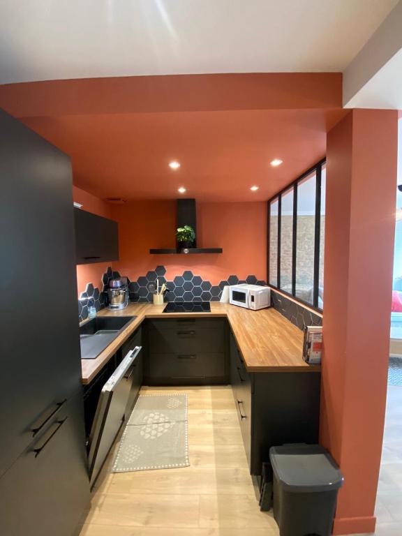 - une cuisine avec des murs orange et un comptoir dans l'établissement Maison normande typique a 150m mer 10 personnes, à Saint-Aubin-sur-Mer