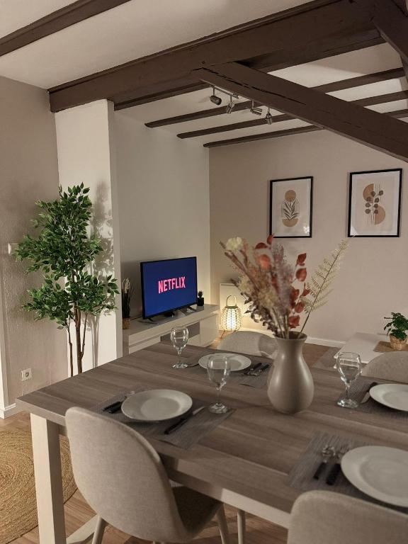 une table à manger avec des chaises et une télévision dans l'établissement Le Cocon de l'Arc, parking free, à Mulhouse