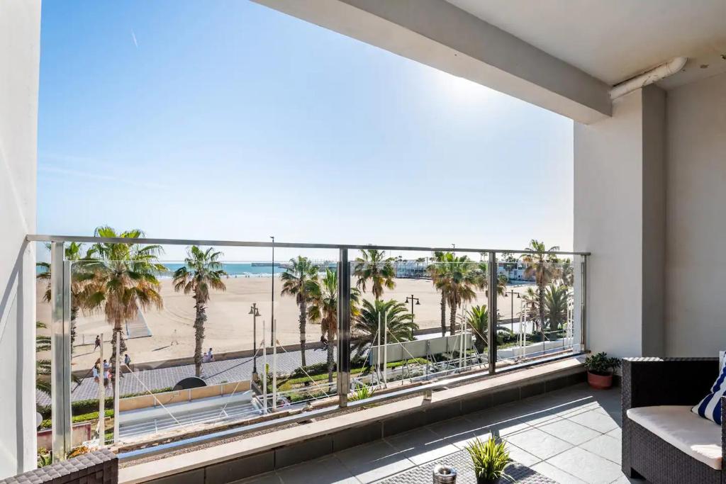 a balcony with a view of the beach and palm trees at Moderno apartamento con vistas al mar en Valencia in Valencia