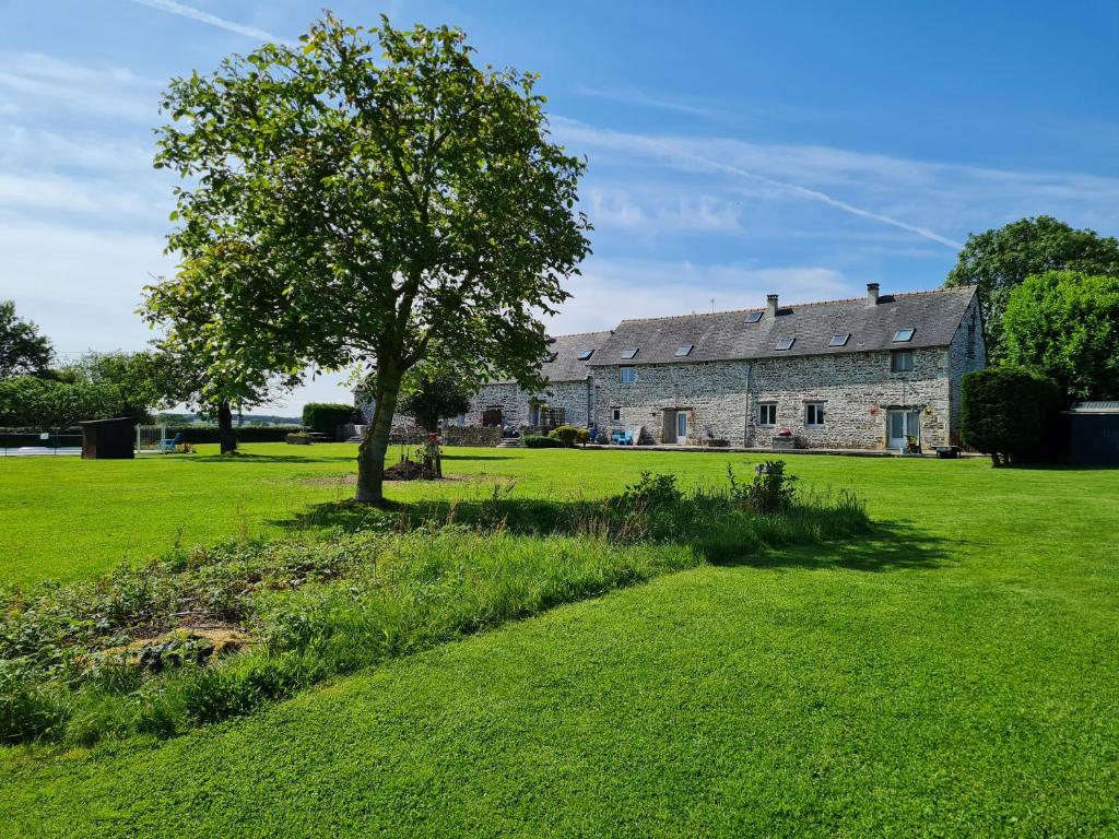 an old stone house with a tree in a field at La Maison Neuve Gîtes in Madré