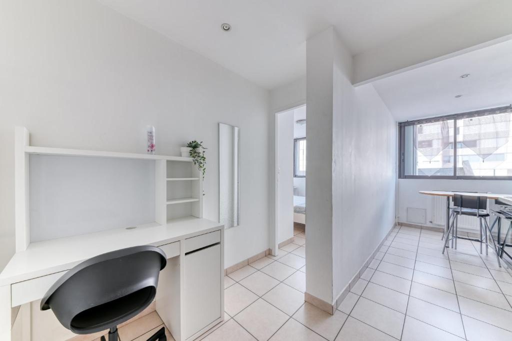 a white kitchen with a desk and a chair at Charming Flat in Villeurbanne Gratte-Ciel in Villeurbanne