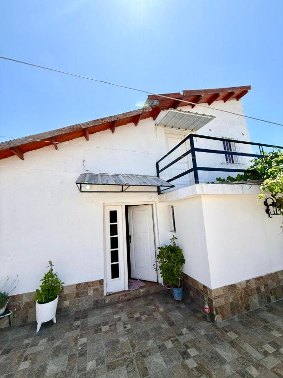 a white house with a door and a balcony at Casa feliza in Villa Dolores