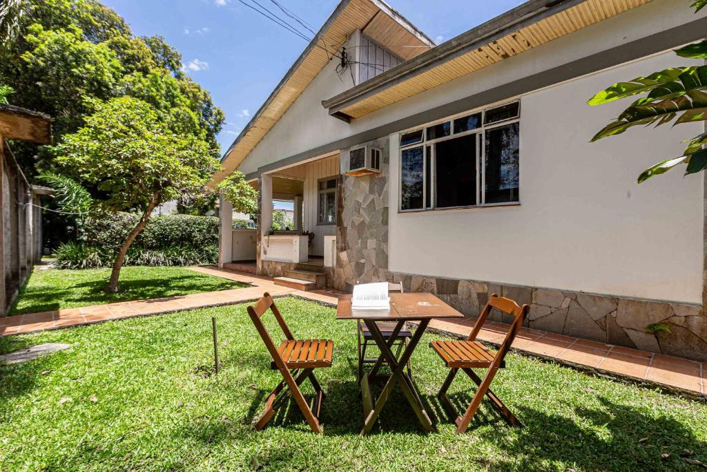 two chairs and a table in the yard of a house at Memora Guesthouse Curitiba - Quartos em Casa próximo ao Parque Bacacheri in Curitiba