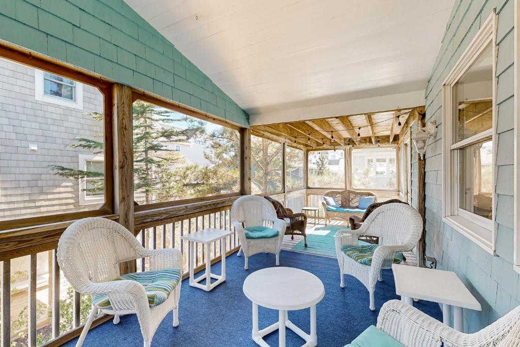 a screened porch with chairs and tables and windows at Ocean Village --- 39679 Willet Rd in Bethany Beach