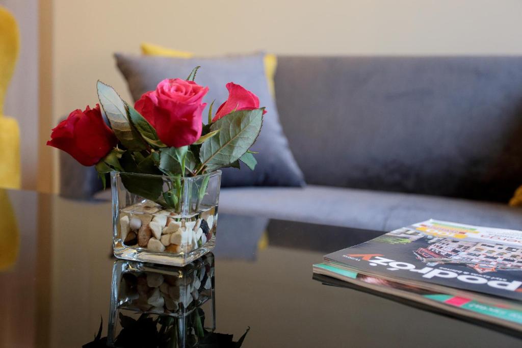 un jarrón con rosas en una mesa junto a un sofá en Apartamenty Zamenhofa, en Białystok