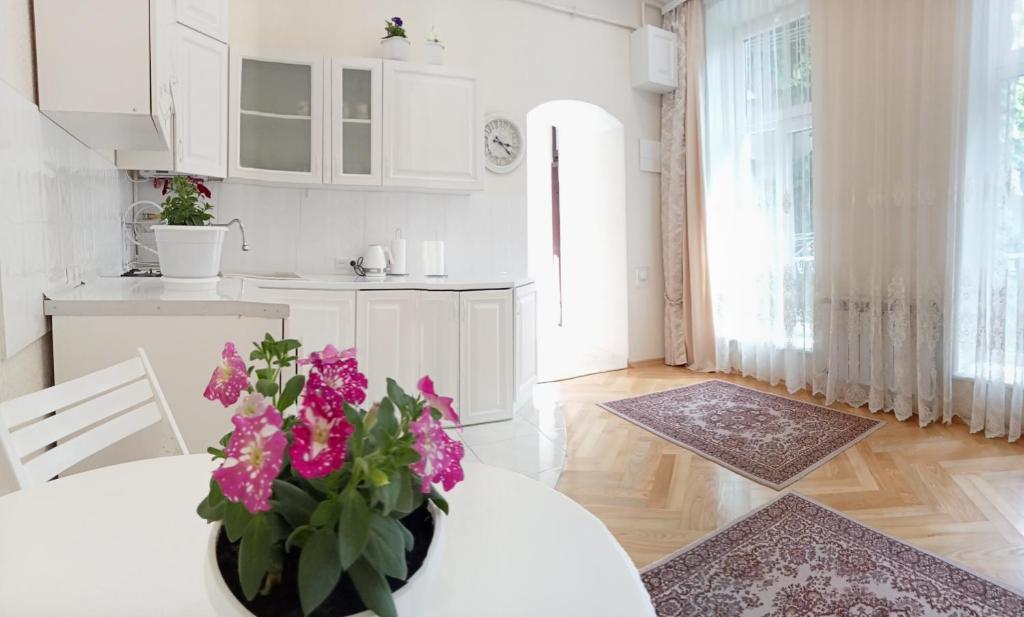 利沃夫Світла затишна квартира в центрі біля Оперного театру з балконом, який виходить у тихий львівський дворик的白色的厨房,配有带鲜花的桌子
