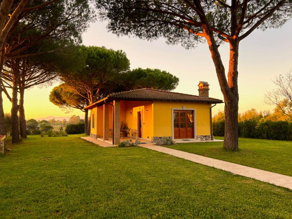 a small yellow house in a field with trees at Tenuta Fiumara in Marina di Grosseto