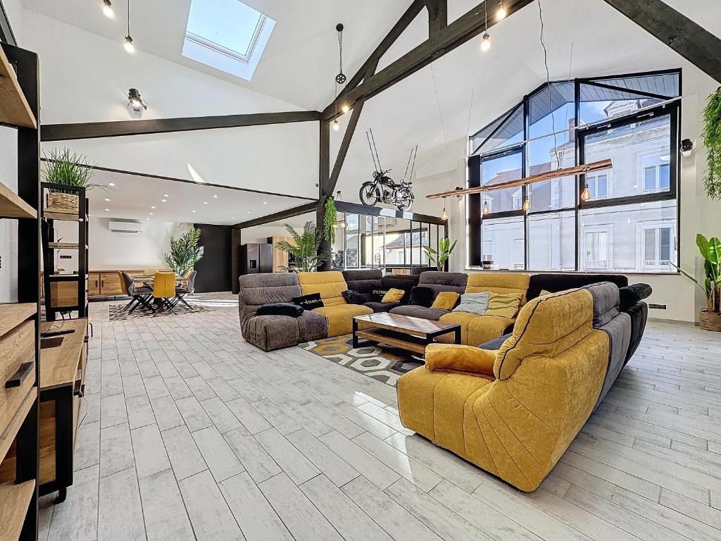 una gran sala de estar con muebles amarillos y una gran ventana. en LOFT SPA SAUNA 10 personnes Centre ville, en Montluçon