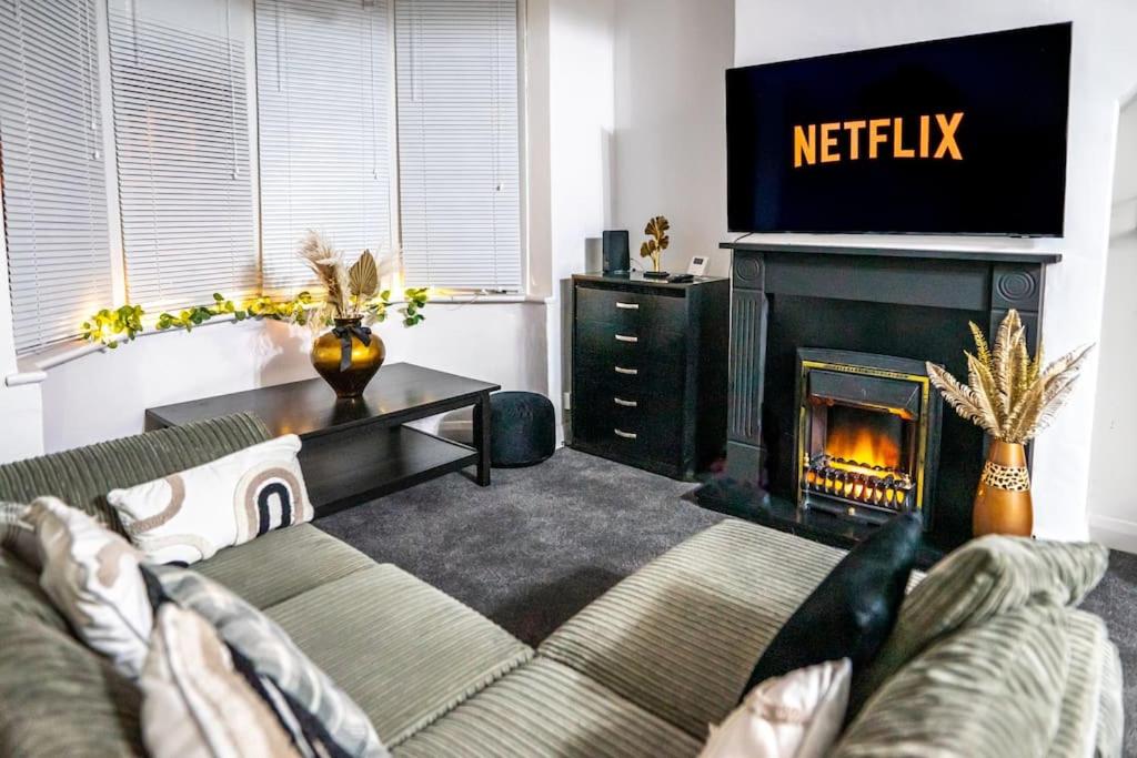 a living room with a couch and a television and a fireplace at The Cave in Coventry