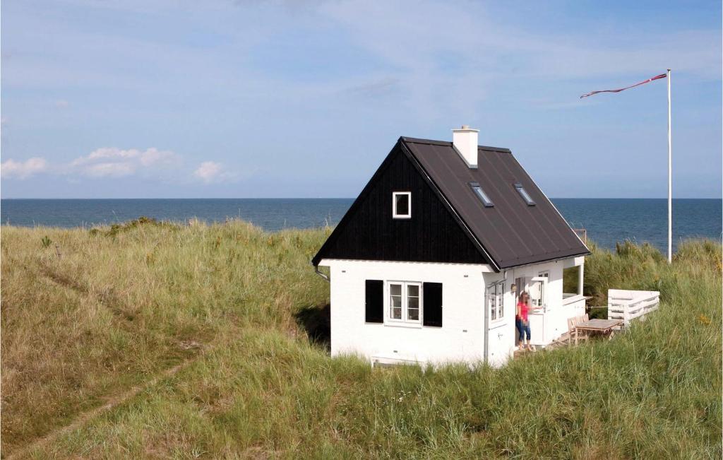 a small white house in the middle of a field at Holiday Home Klitmarken Strandby X in Strandby