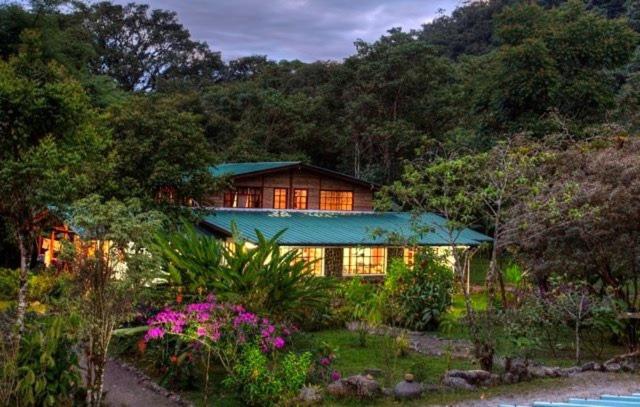 ein Haus mit grünem Dach im Wald in der Unterkunft Rio Quijos EcoLodge in El Chaco