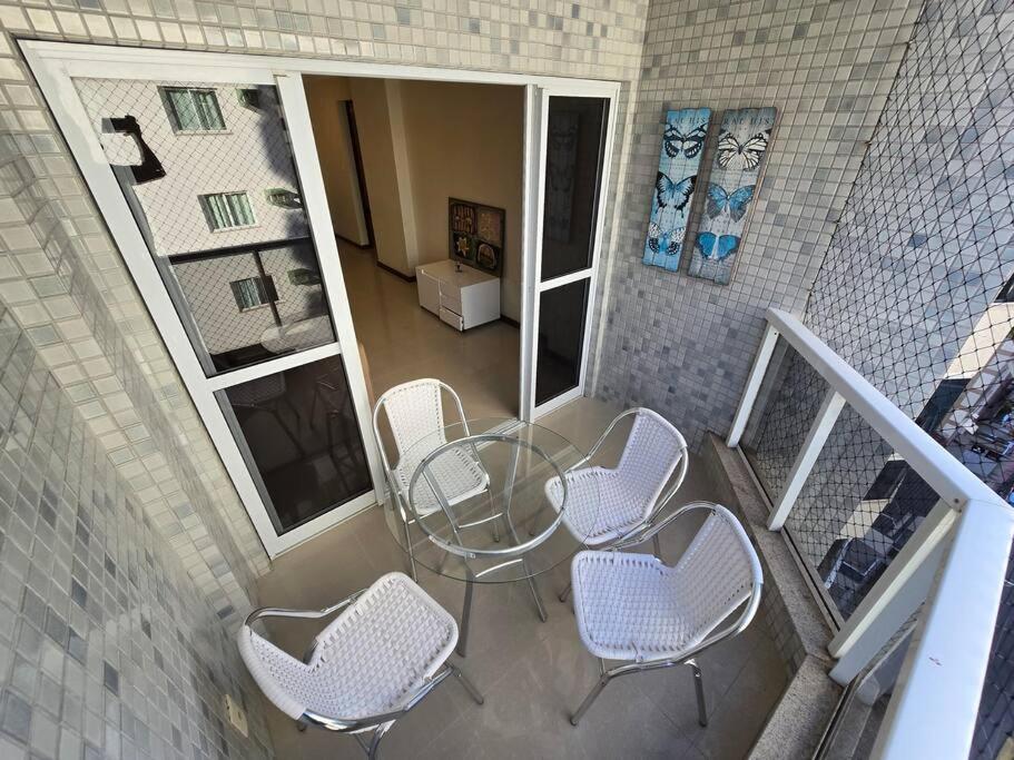 a balcony with a glass table and chairs at Lindo Apt Beira Mar Guarapari in Guarapari