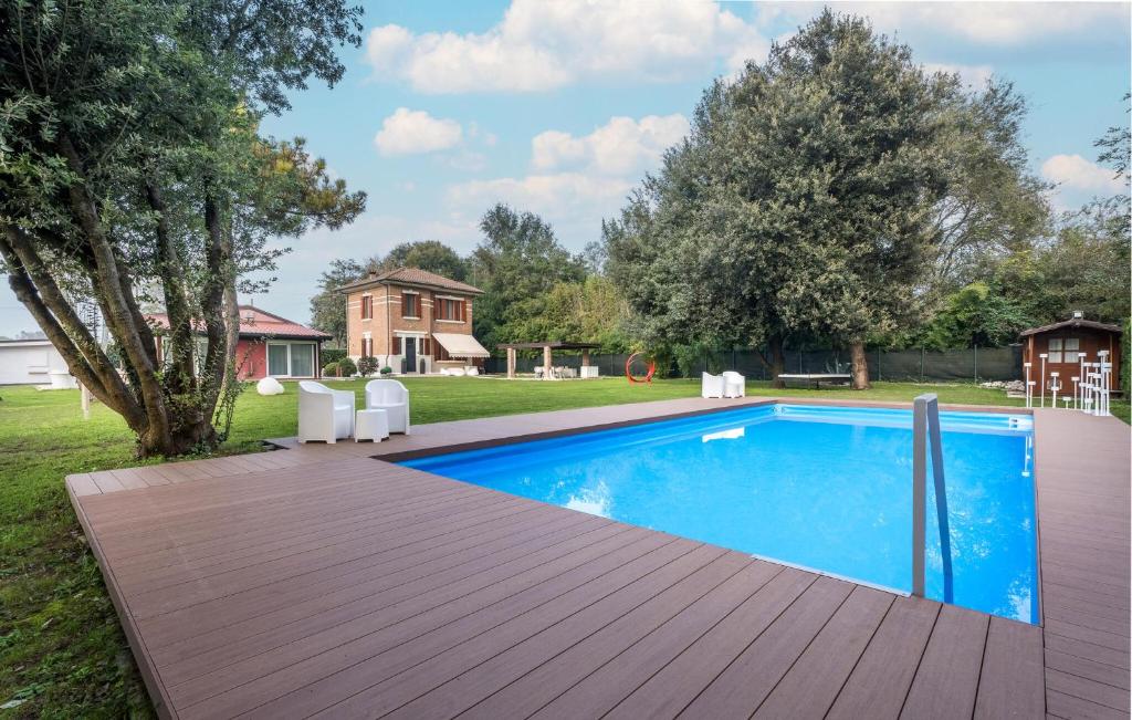 a swimming pool with a wooden deck next to a yard at 3 Bedroom Nice Home In Rosolina in Rosolina