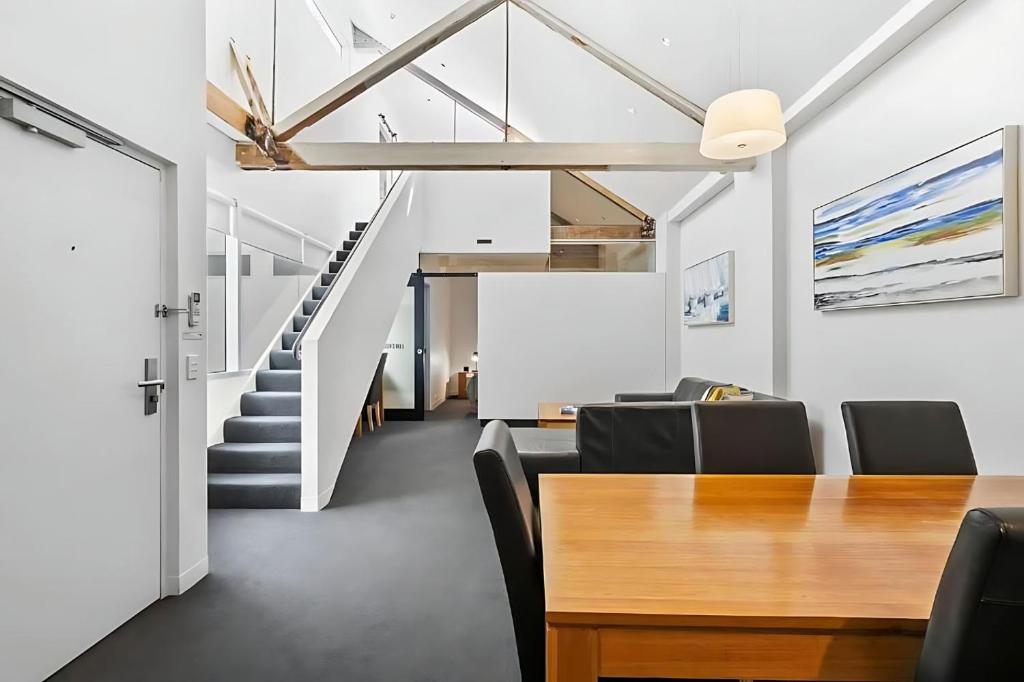 a dining room with a table and a staircase at Gibson Mill waterfront loft apartment - 304 in Hobart