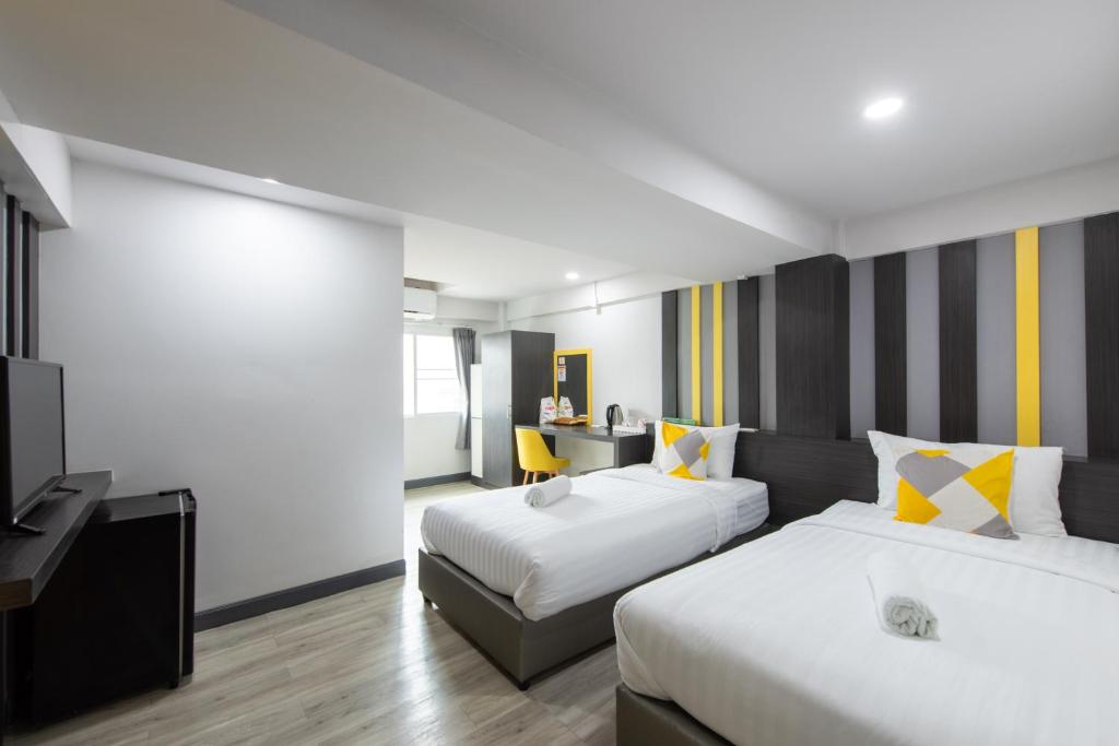 a hotel room with two beds and a television at Riski Residence Bangbuathong in Nonthaburi