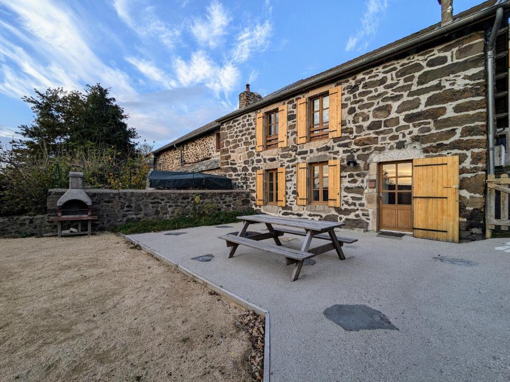 a picnic table in front of a stone building at Gîte familial en Haute-Loire avec terrain clos, à proximité de l'Ardèche et des stations de ski - FR-1-582-236 in Freycenet-la-Tour