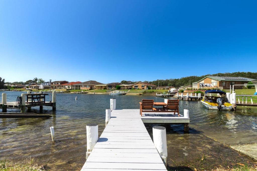 a dock with benches and a boat in the water at Bayt Baytak in Sussex inlet