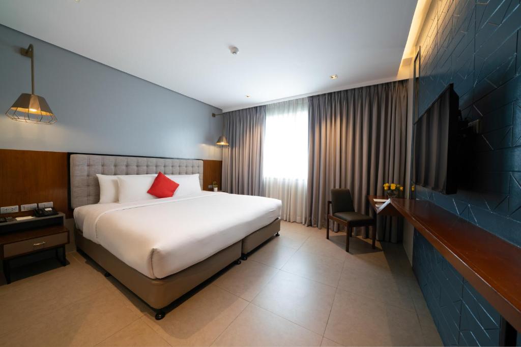a hotel room with a bed and a television at Summit Galleria Cebu in Cebu City