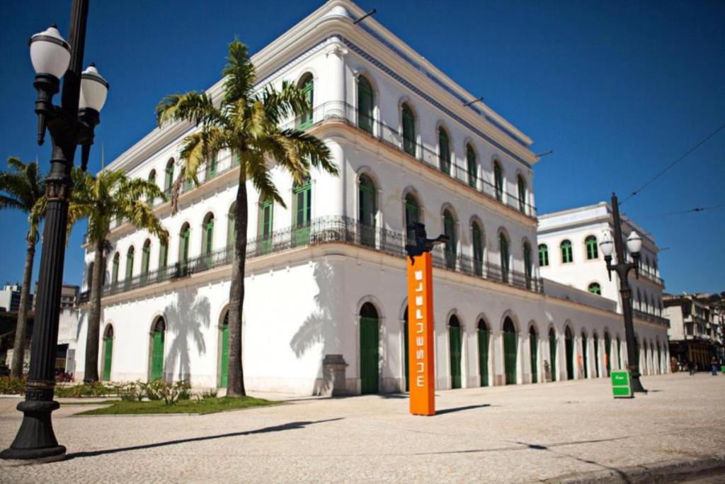 a large white building with a palm tree in front of it at Apartamento 412B com varanda e vista in Santos