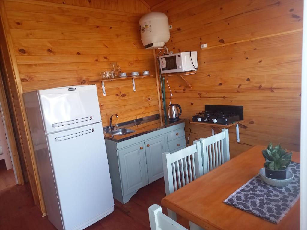 Una cocina con un refrigerador blanco y una mesa. en Cabaña Don Juan, en Villa Elisa