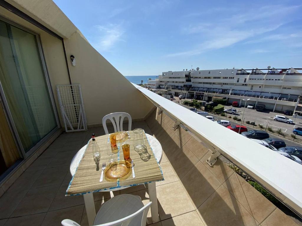 une table sur un balcon avec vue sur une ville dans l'établissement Studio cabine 4 pers, terrasse, parking, Cap d'Agde naturiste - FR-1-249A-42, au Cap d'Agde