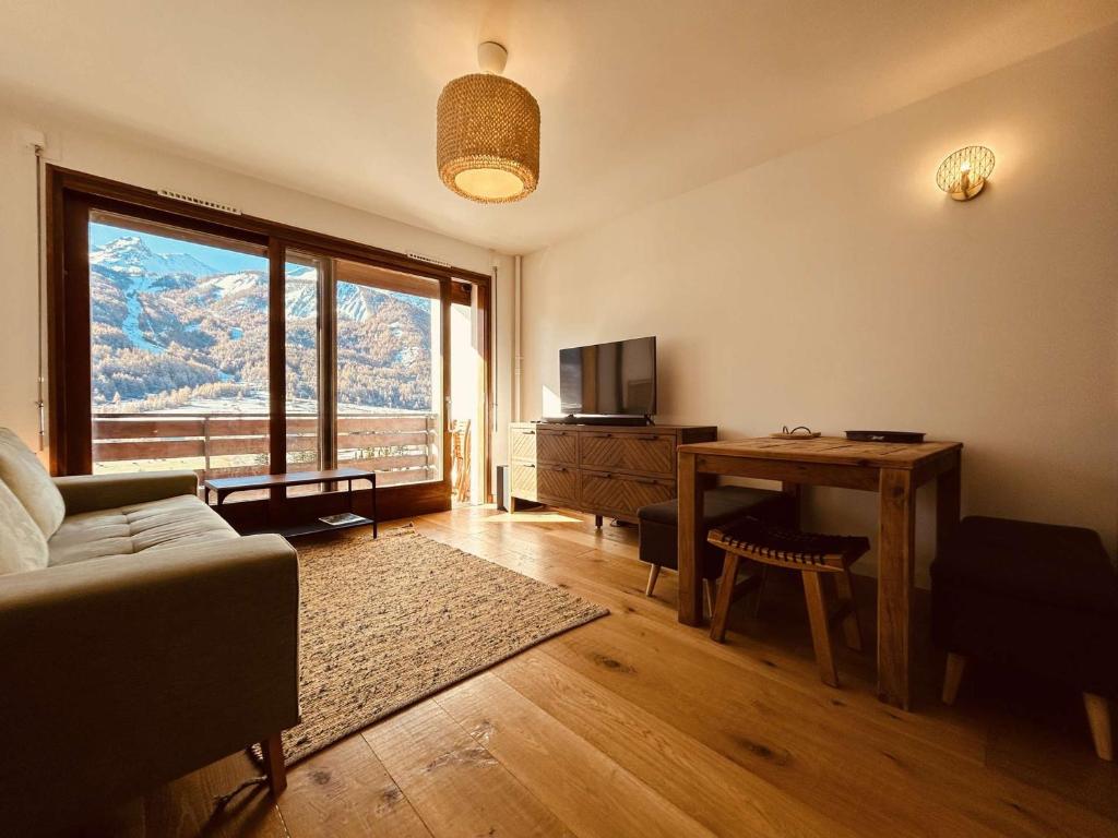 un salon avec une table et un bureau avec une télévision dans l'établissement Studio cabine 4 pers. à Monêtier-les-Bains, parking, balcon avec vue montagne - FR-1-330F-242, au Monêtier-les-Bains