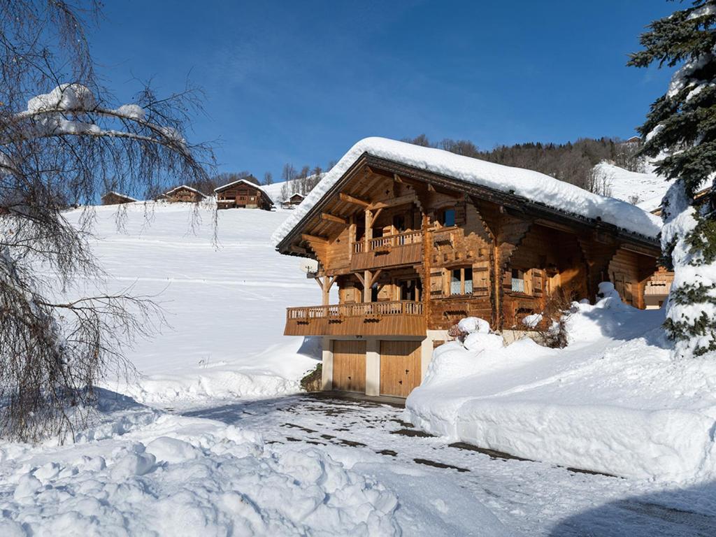 une cabane en rondins est couverte de neige dans l'établissement Chalet spacieux 10 pers. près pistes ski, parking privé - FR-1-467-135, au Grand-Bornand