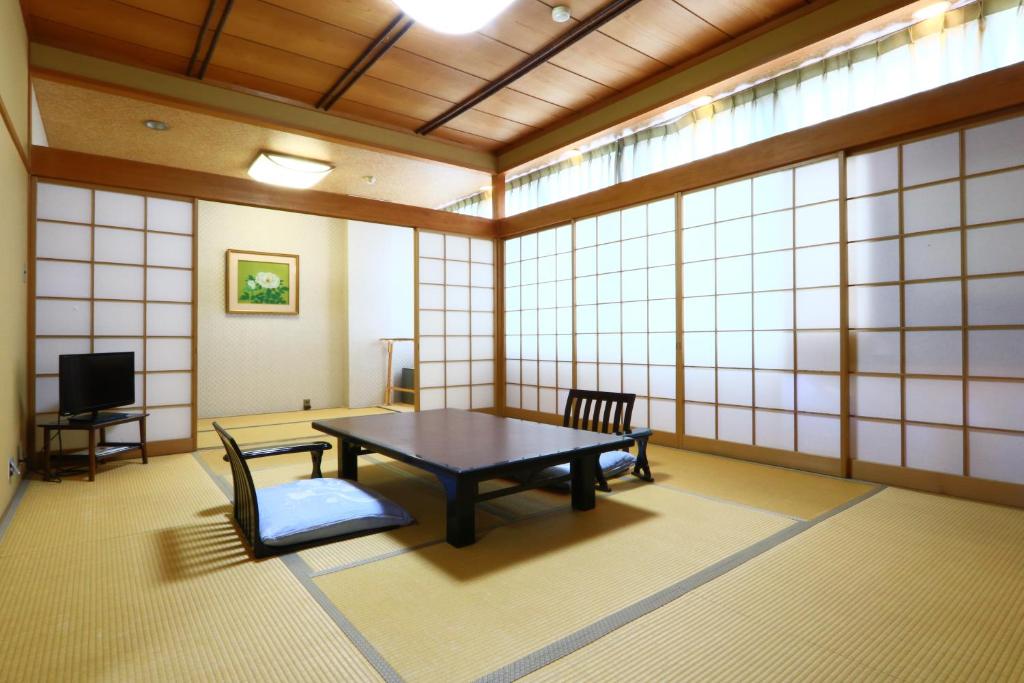 a room with a table and chairs and a tv at 割烹旅館小川荘 in Ōmiya