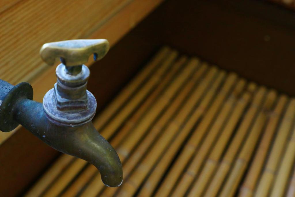 a close up of a metal faucet next to a bench at 割烹旅館小川荘 in Ōmiya