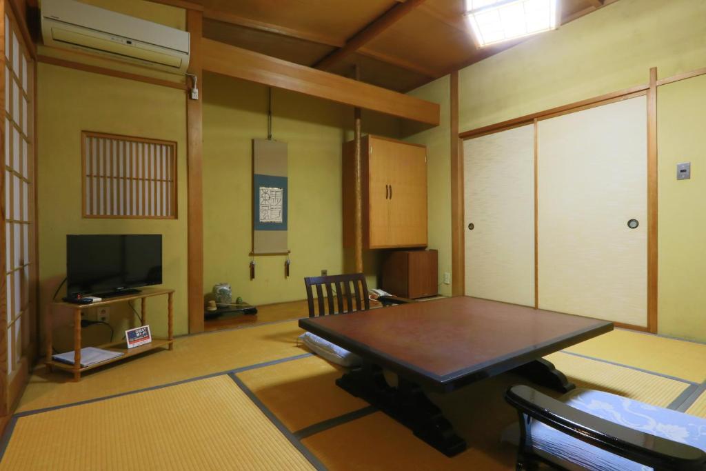 a room with a table and a tv in a room at 割烹旅館小川荘 in Ōmiya