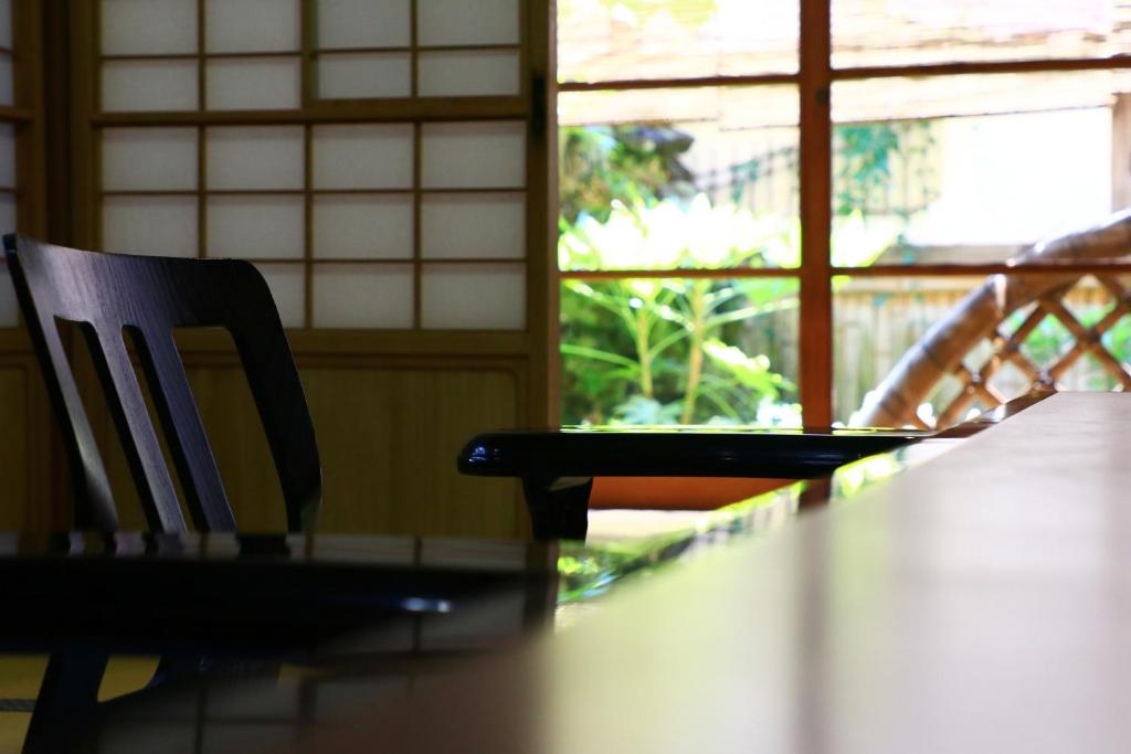 a wooden table with a chair next to a window at 割烹旅館小川荘 in Ōmiya