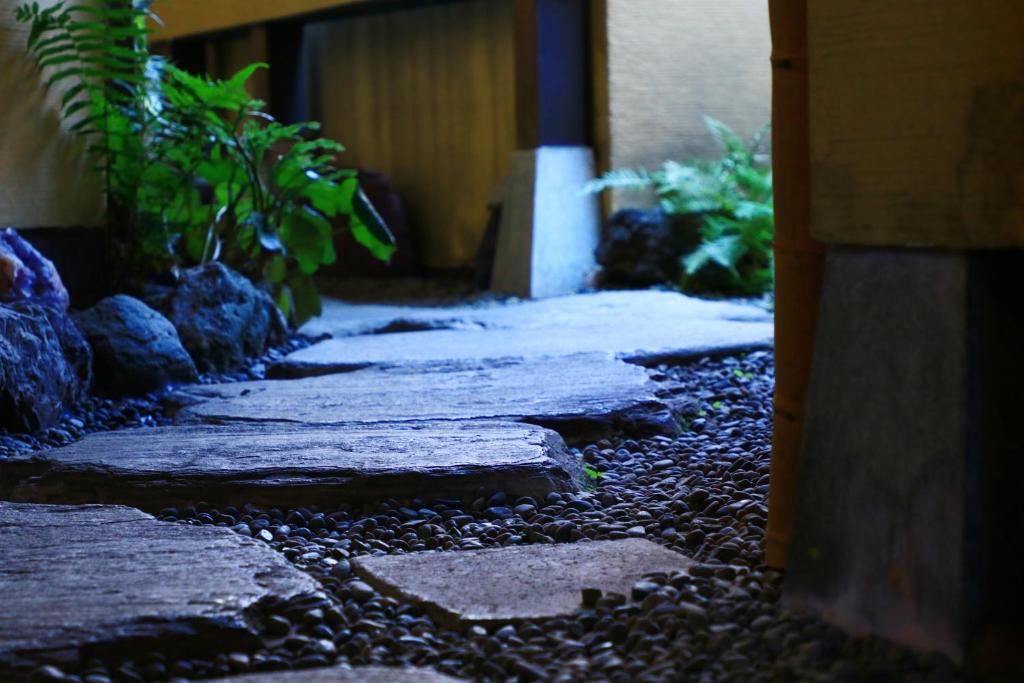 a walkway with rocks and plants in front of a building at 割烹旅館小川荘 in Ōmiya