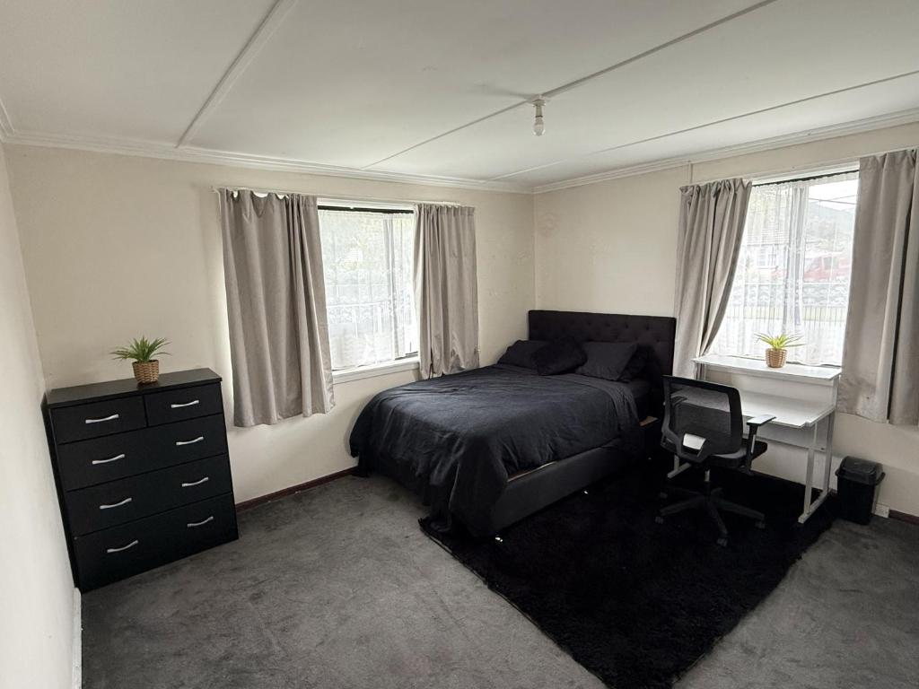 une chambre avec un lit, un bureau et des fenêtres dans l'établissement Pet friendly house with hot tub, à Lower Hutt