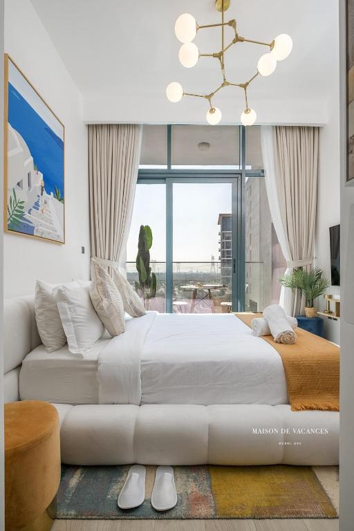 a white bedroom with a large bed and a chandelier at Santorini Studio Pool View in Dubai