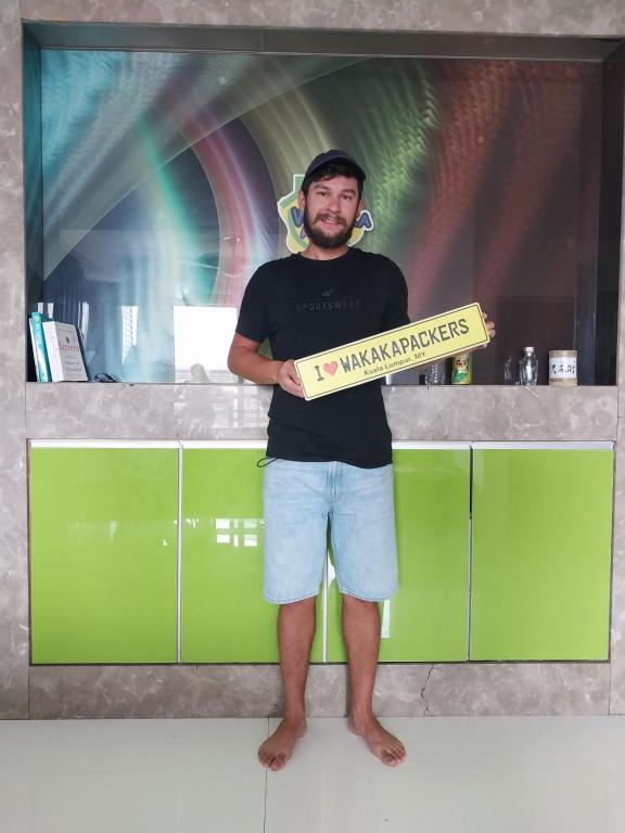 a man standing in a kitchen holding a pizza box at WakakaPackers in Kuala Lumpur