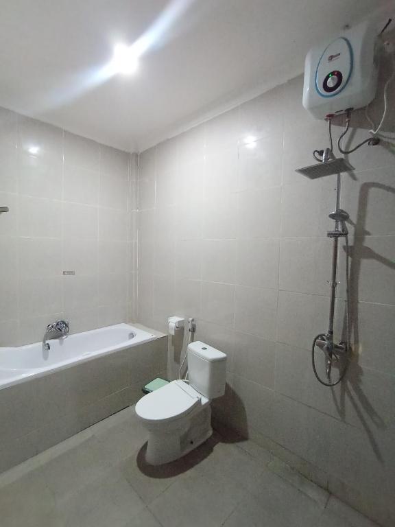 a bathroom with a toilet and a bath tub at Hotel Green Prundi in Labuan Bajo