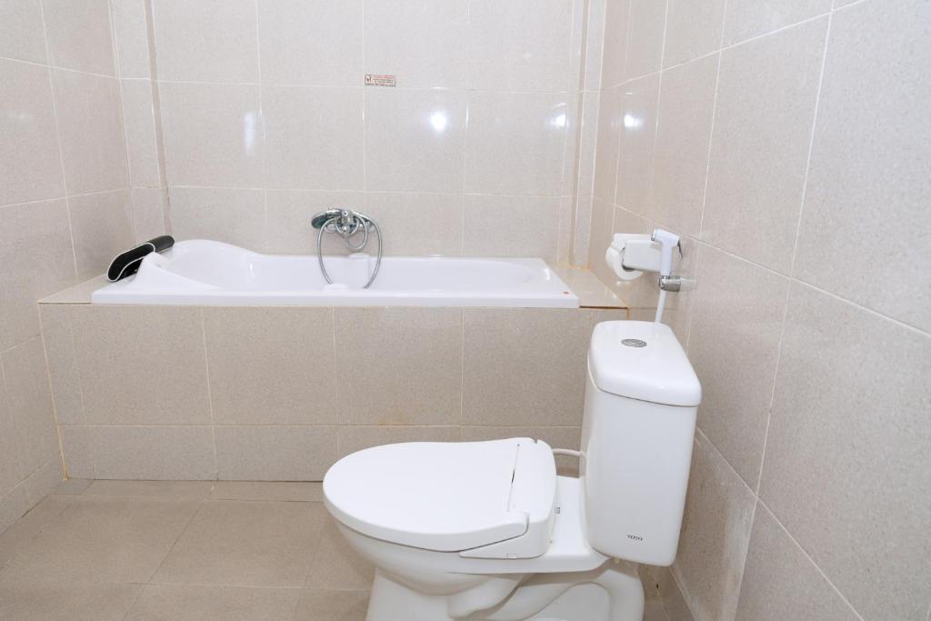 a bathroom with a toilet and a bath tub at Hotel Green Prundi in Labuan Bajo