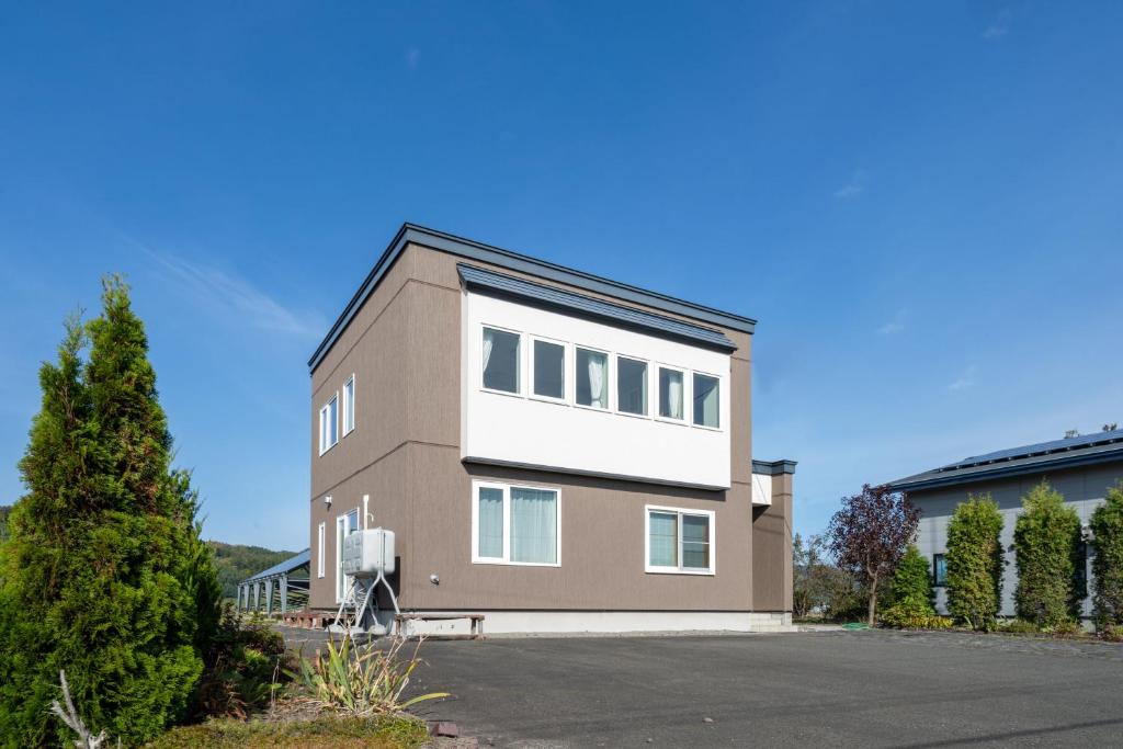 een bruin en wit gebouw met veel ramen bij Clematis in Nakafurano