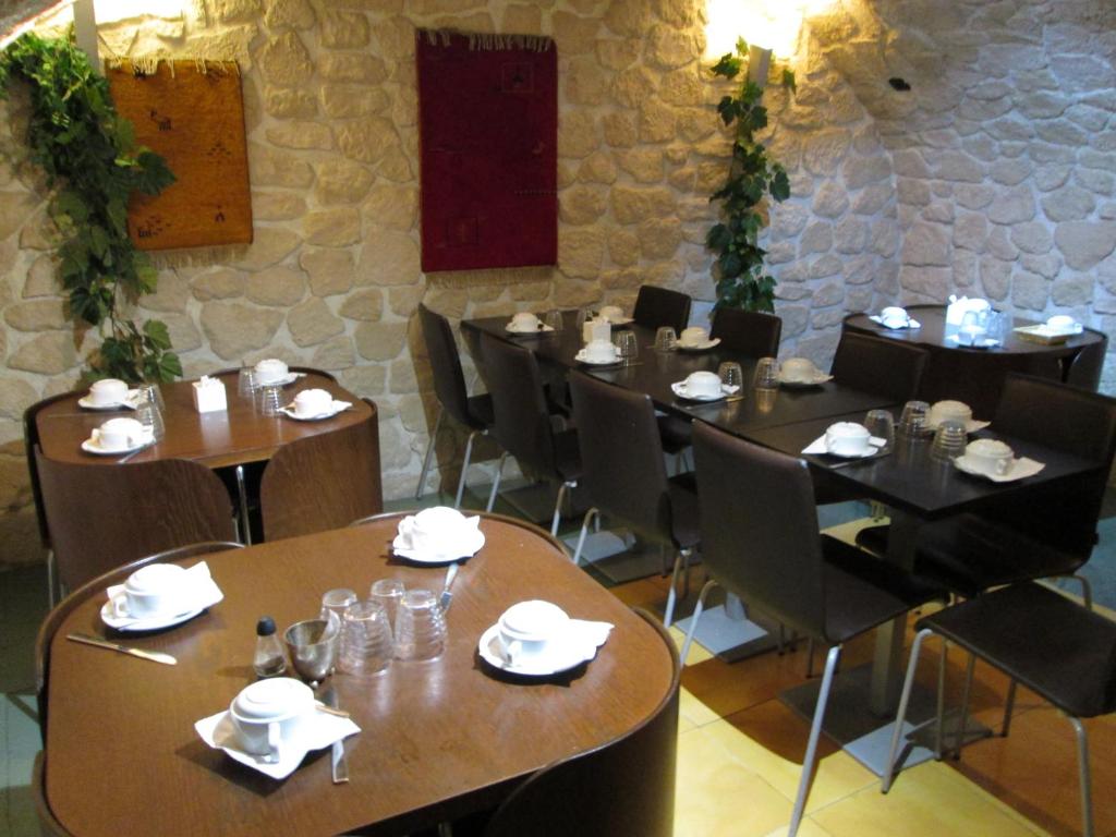 comedor con mesas y sillas y pared de piedra en Hotel Hauteville Opera, en París