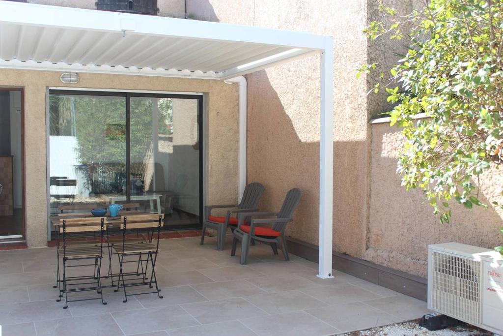 une terrasse avec des chaises, une table et une pergola blanche. dans l'établissement T2 climatisé à 2 minutes de la plage du Pont Tournant - 4BRANB, à Saint Cyprien Plage